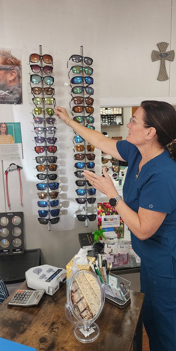 Andrea Baker showing a customer the sunglasses wall at her optical shop in Burnet, TX